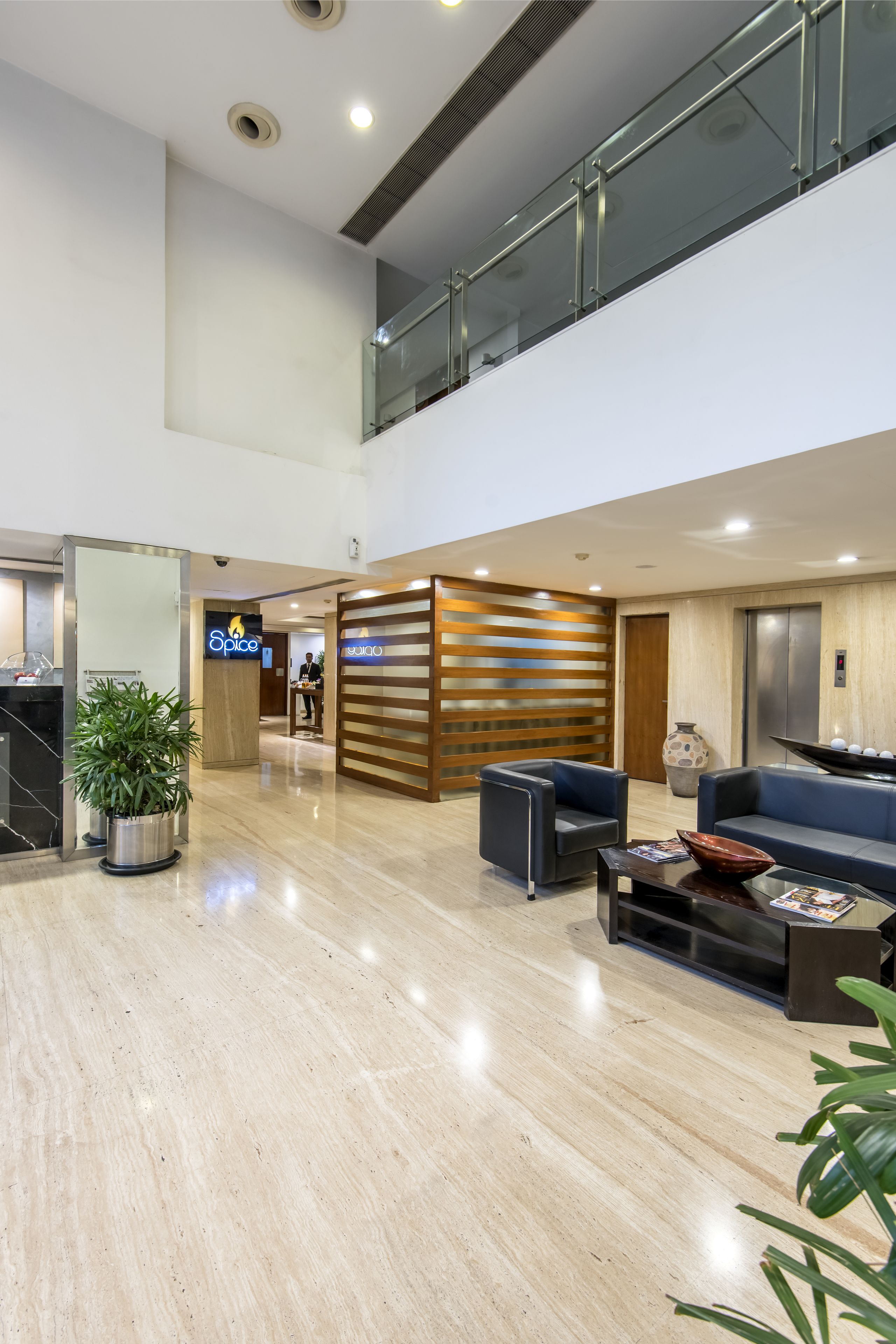 Eine geräumige Lobby mit modernem Design, inklusive einer Rezeption, einer Sitzecke und einer Treppe zu einer oberen Ebene.