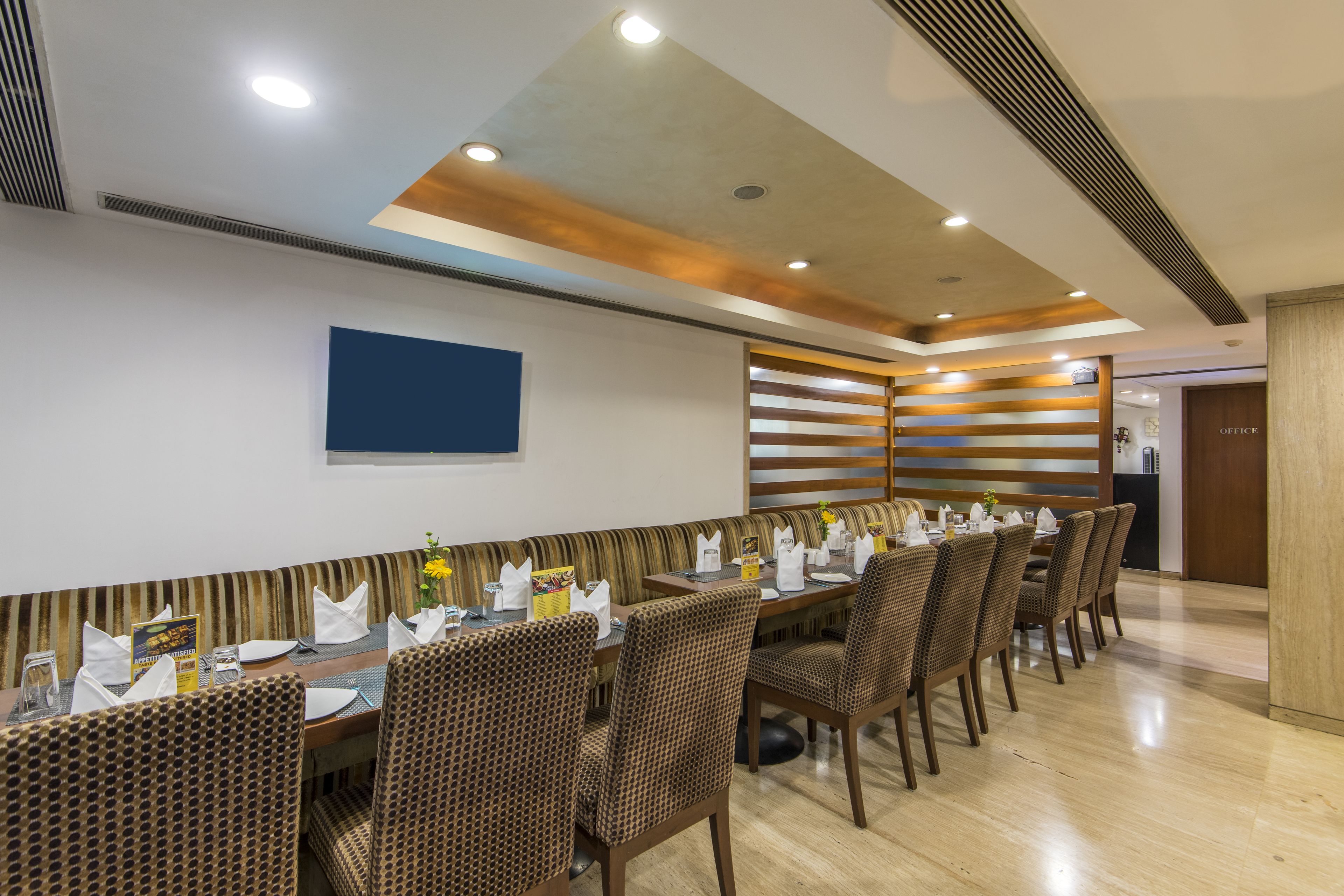 A dining area with a long table set for multiple people, chairs, and a wall-mounted menu board.