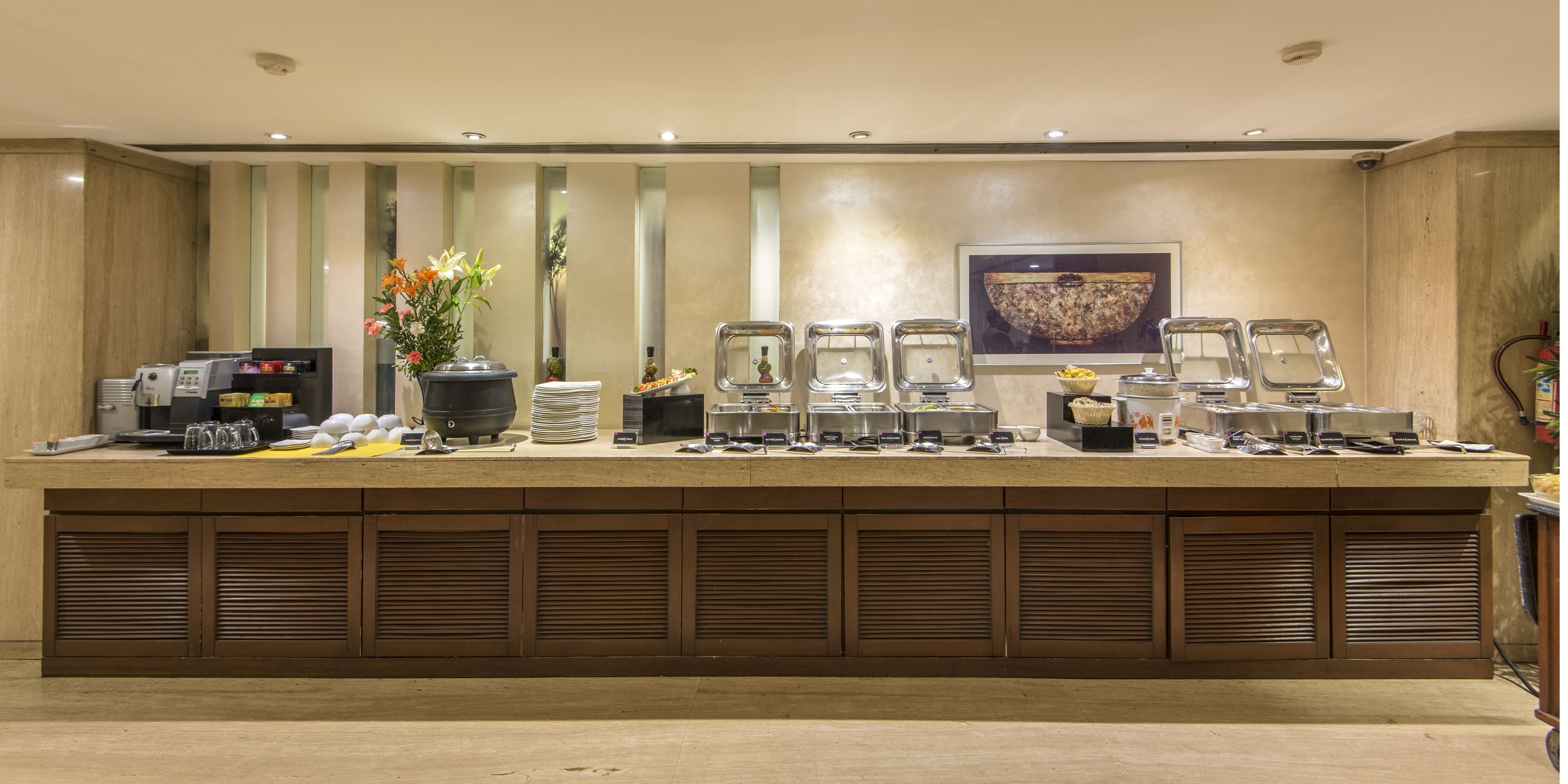 Ein Buffet mit verschiedenen Speiseausgaben, einer Kaffeemaschine und einer dekorativen Vase mit Blumen.