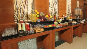 A buffet with various food items and beverages, including fruits, salads, and drinks. - Phoenix Hotel (Pune)