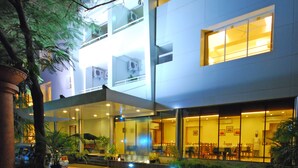 A modern hotel with a covered outdoor seating area, a tiled walkway, and a large window overlooking the interior. - Phoenix Hotel (Pune)