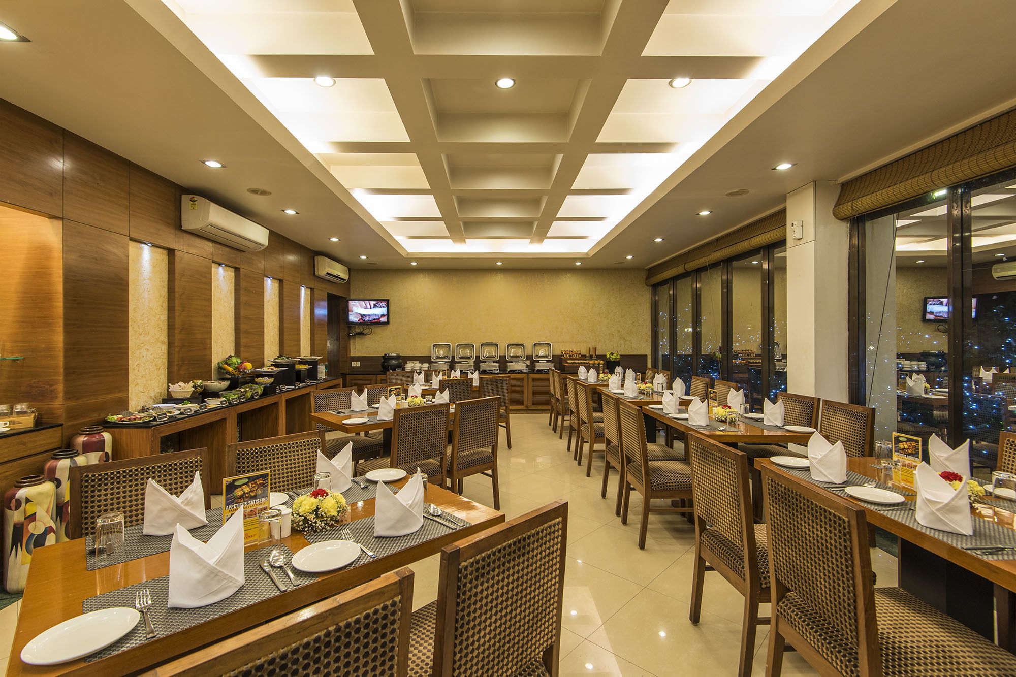 A restaurant with multiple dining tables, chairs, and a television screen.
