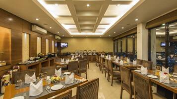 A restaurant with multiple dining tables, chairs, and a television screen.