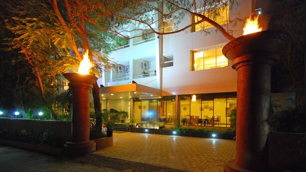 A hotel entrance with a paved walkway, large columns, and a glass facade. - Phoenix Hotel (Pune)
