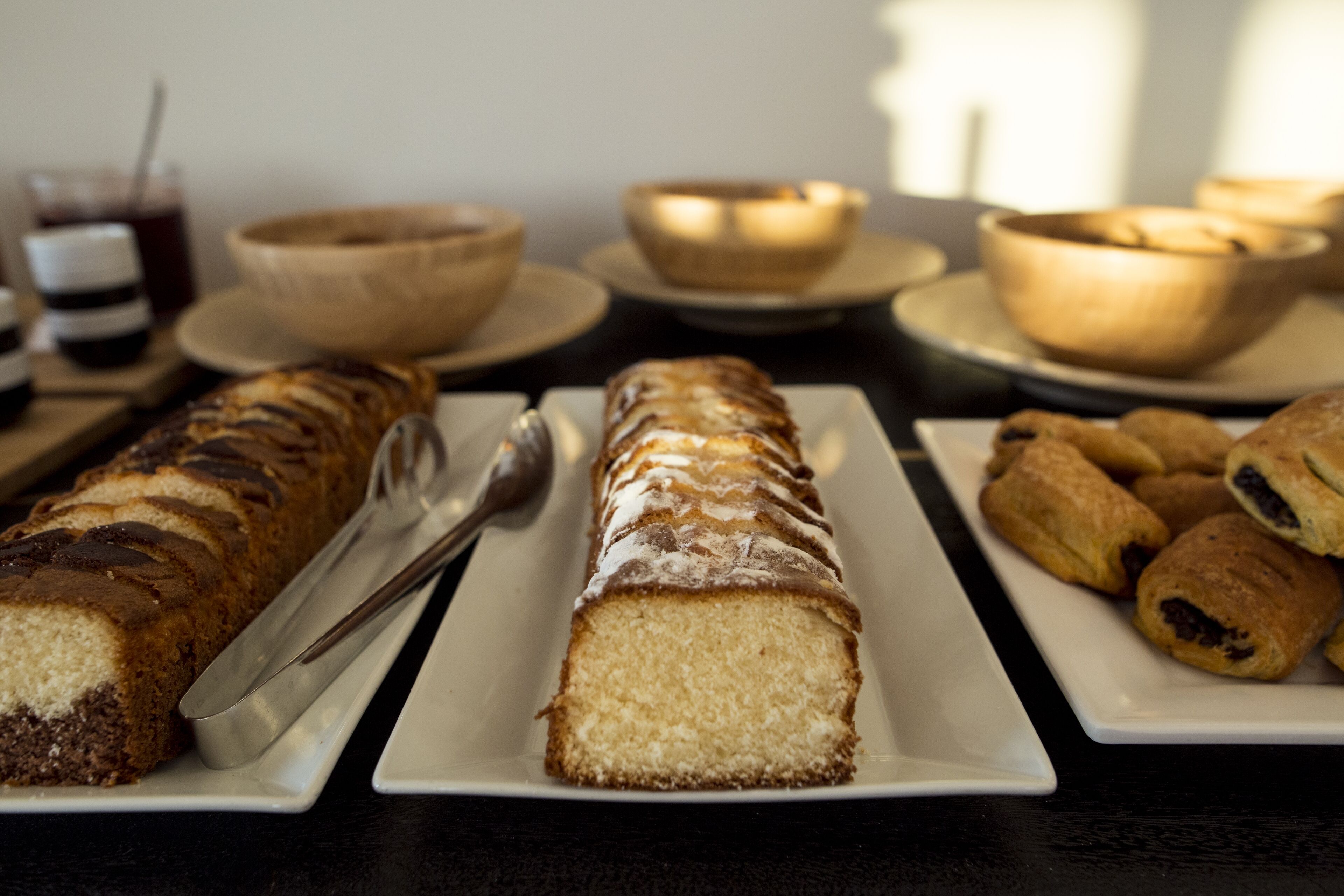 A table with a variety of baked goods, including a loaf of bread, pastries, and a cake.