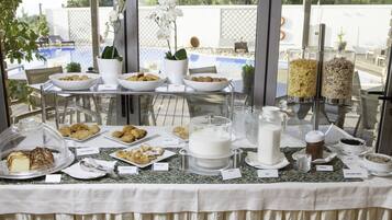 A buffet table with various food items and a view of a swimming pool.