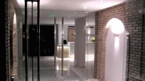 Um lobby de hotel moderno com divisória de vidro, balcão de recepção e parede de tijolos.