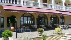 Ein Gebäude mit überdachter Außenbestuhlung, mehreren Balkonen und einer gefliesten Terrasse.