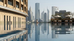 A serene indoor pool with a person meditating, surrounded by modern buildings and lounge chairs. - Kempinski Central Avenue Dubai (Dubai)