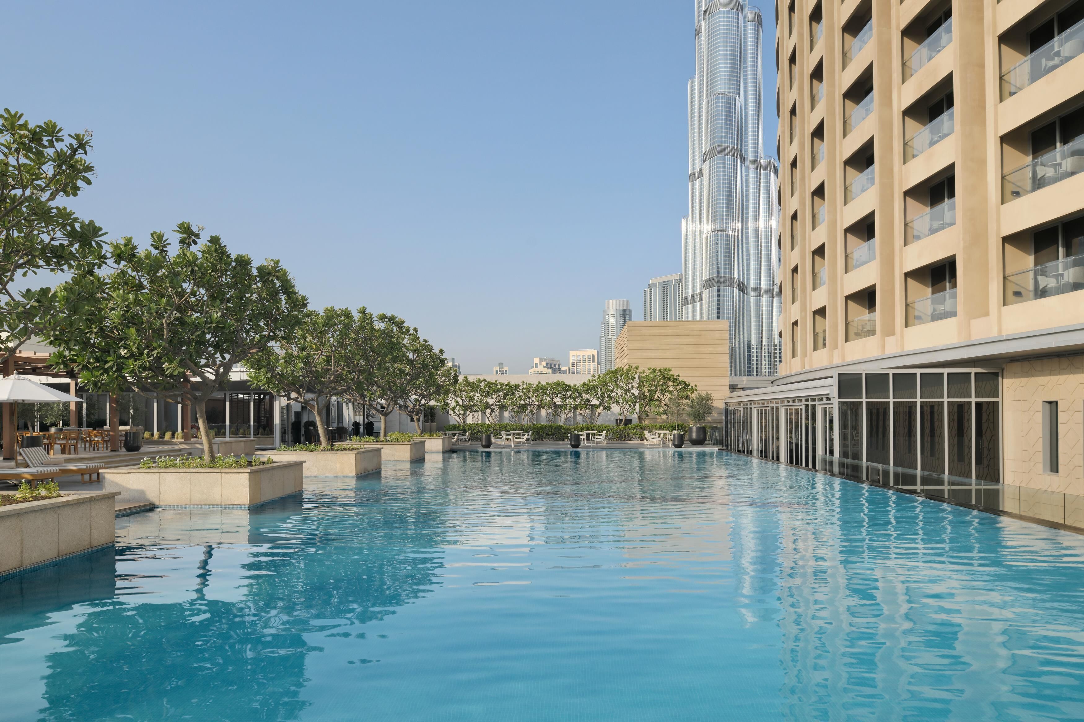 A swimming pool with lounge chairs and a view of a tall building.