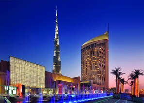 A modern hotel with a prominent tower, a large building with patterned facade, and a well-lit fountain area. - Kempinski Central Avenue Dubai (Dubai)