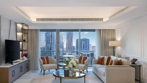 A modern living room with a television, sofa, coffee table, and a view of the cityscape through large windows.