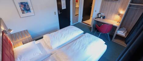 A hotel room with two beds, a desk, a TV, and a red chair.