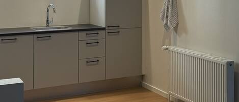 A modern kitchen with a built-in oven, a sink, and a window above the counter.