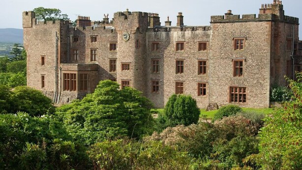 A castle with stone walls, multiple windows, and a flag. - The Coachman's Quarters at Muncaster Castle (Ravenglass)