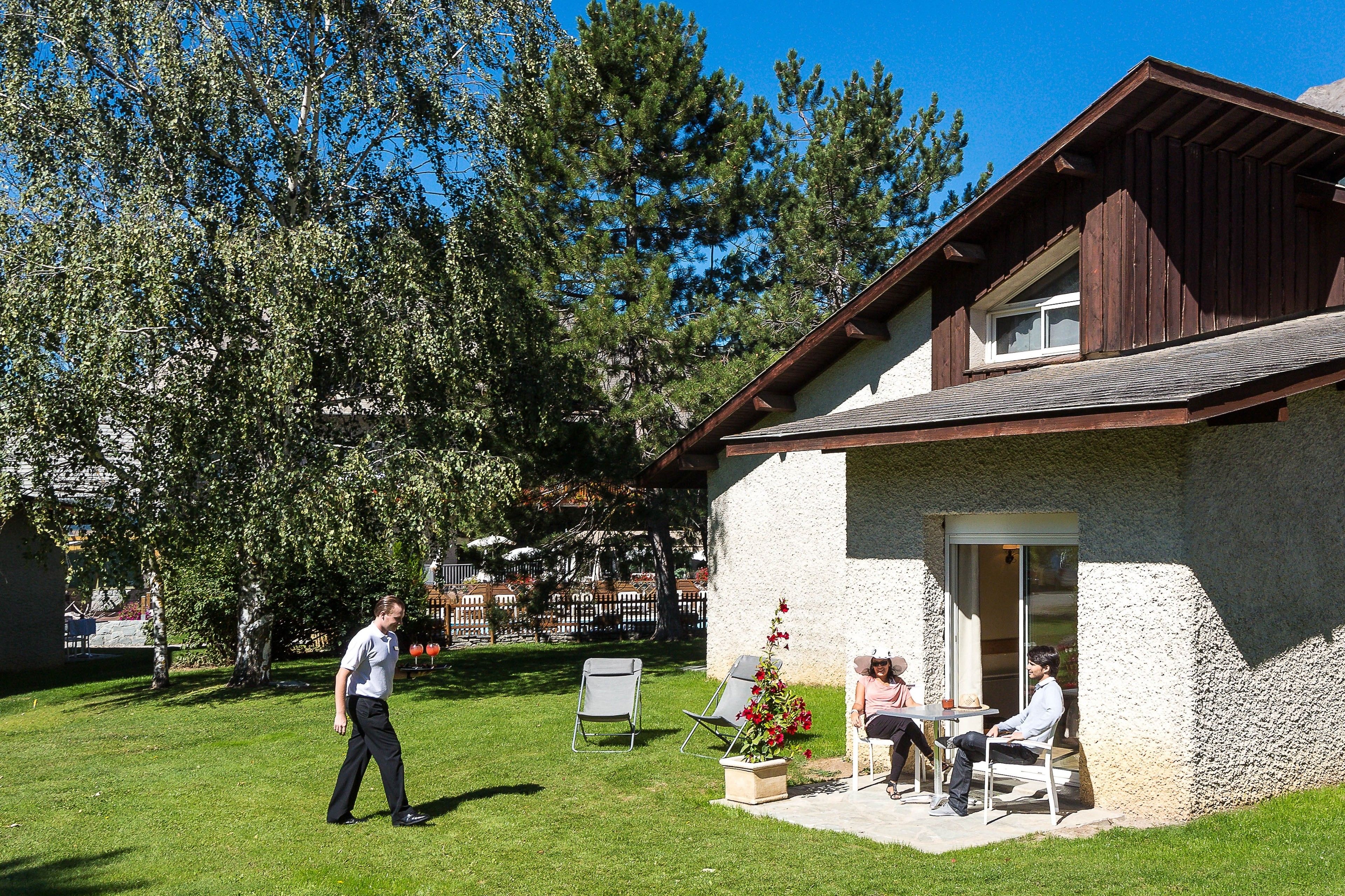 A house with a patio area, a lawn, and a tree.