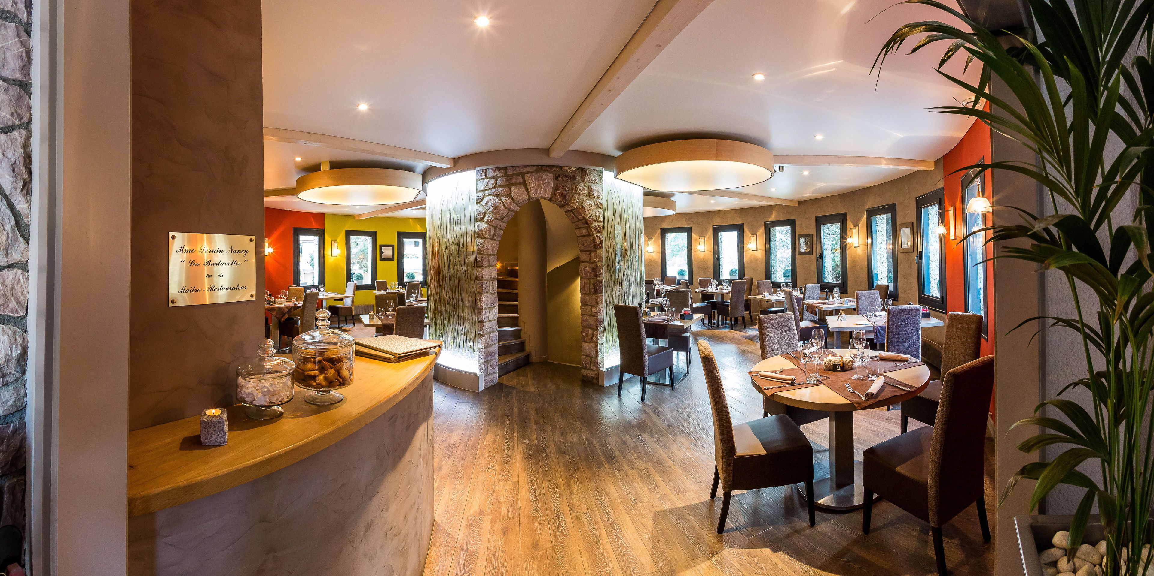 Ein Restaurant mit steinernen Rundbögen, Holzdielen und mehreren Essplätzen.