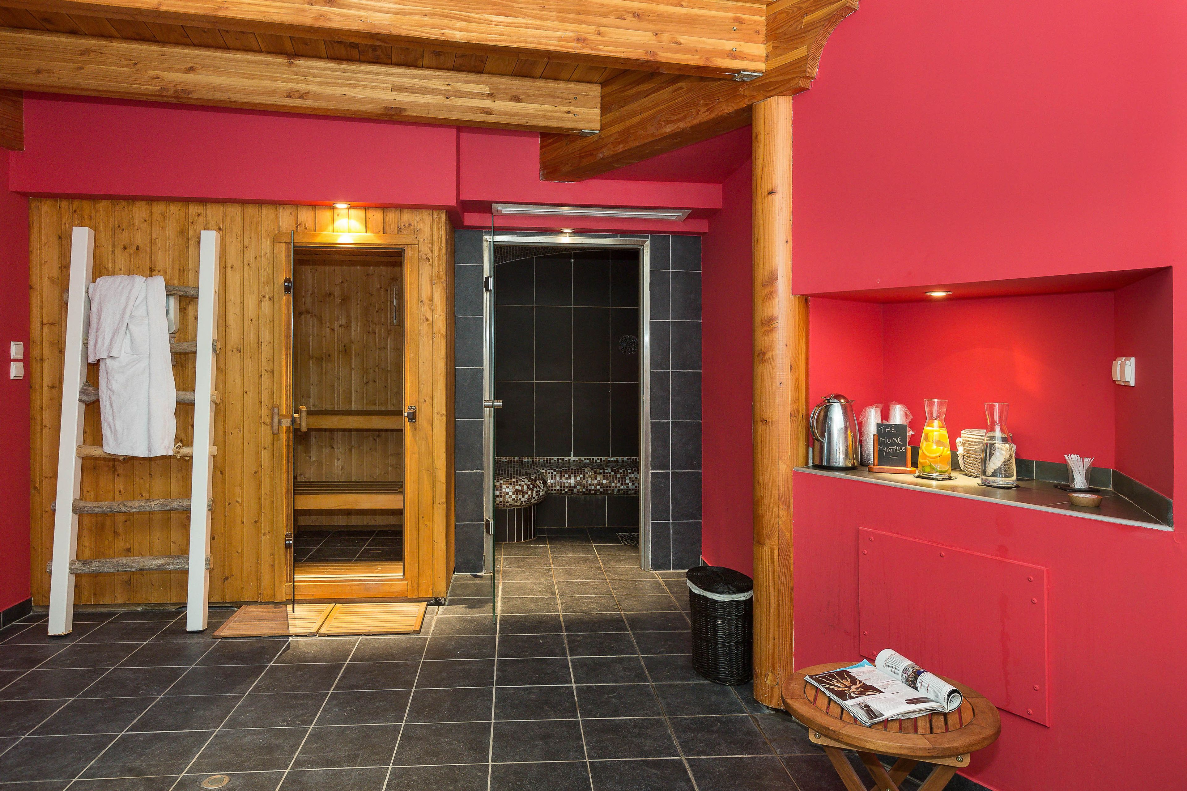 A sauna room with a wooden ladder, a towel rack, and a tiled floor.