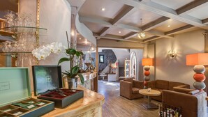 Vestíbulo de hotel con mostrador de recepción, zona de estar y elementos decorativos como orquídeas y lámparas.