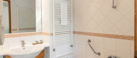 A bathroom with a sink, mirror, towel rack, and a bathtub.