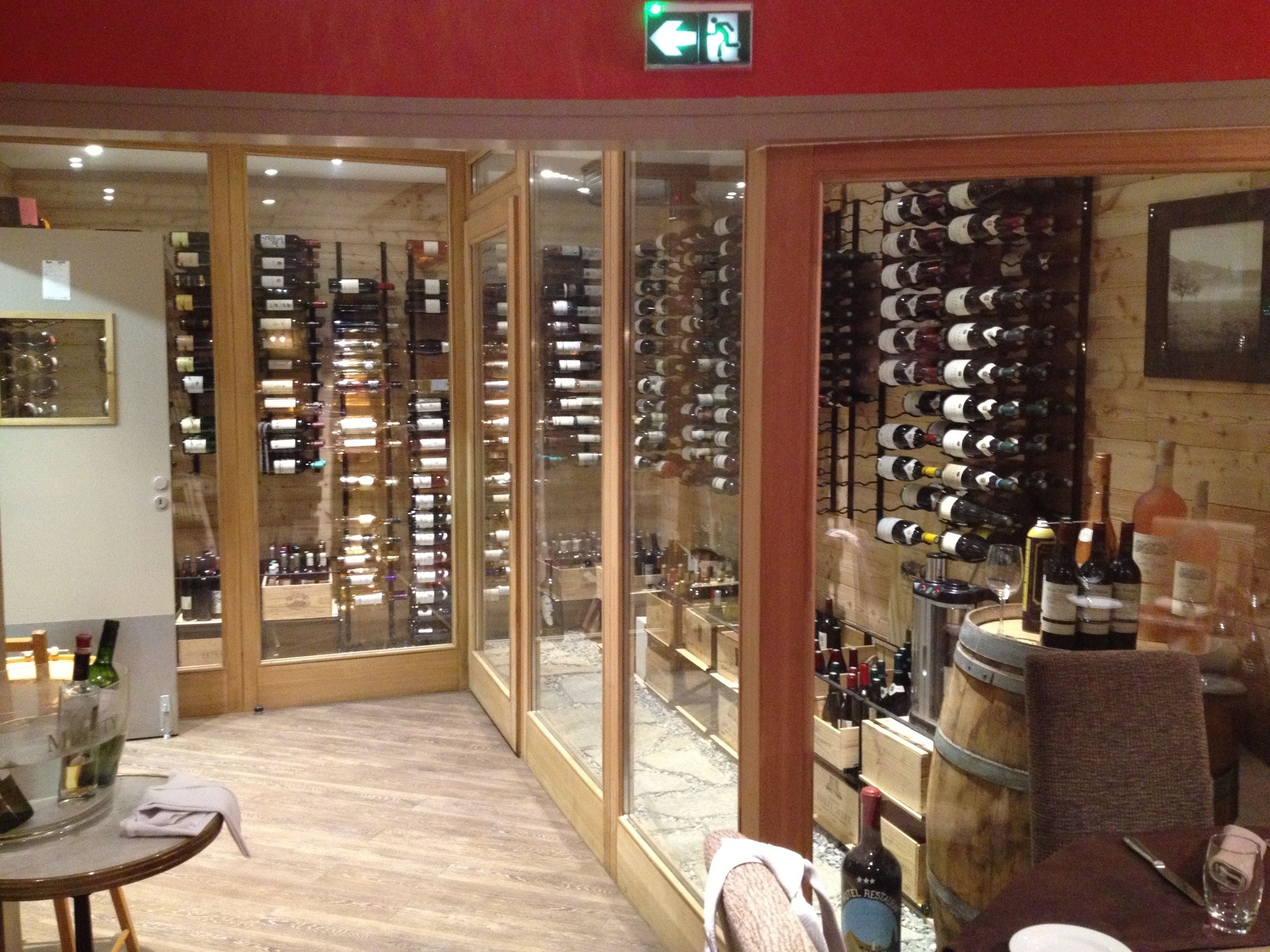 A wine cellar with wooden racks and glass doors.