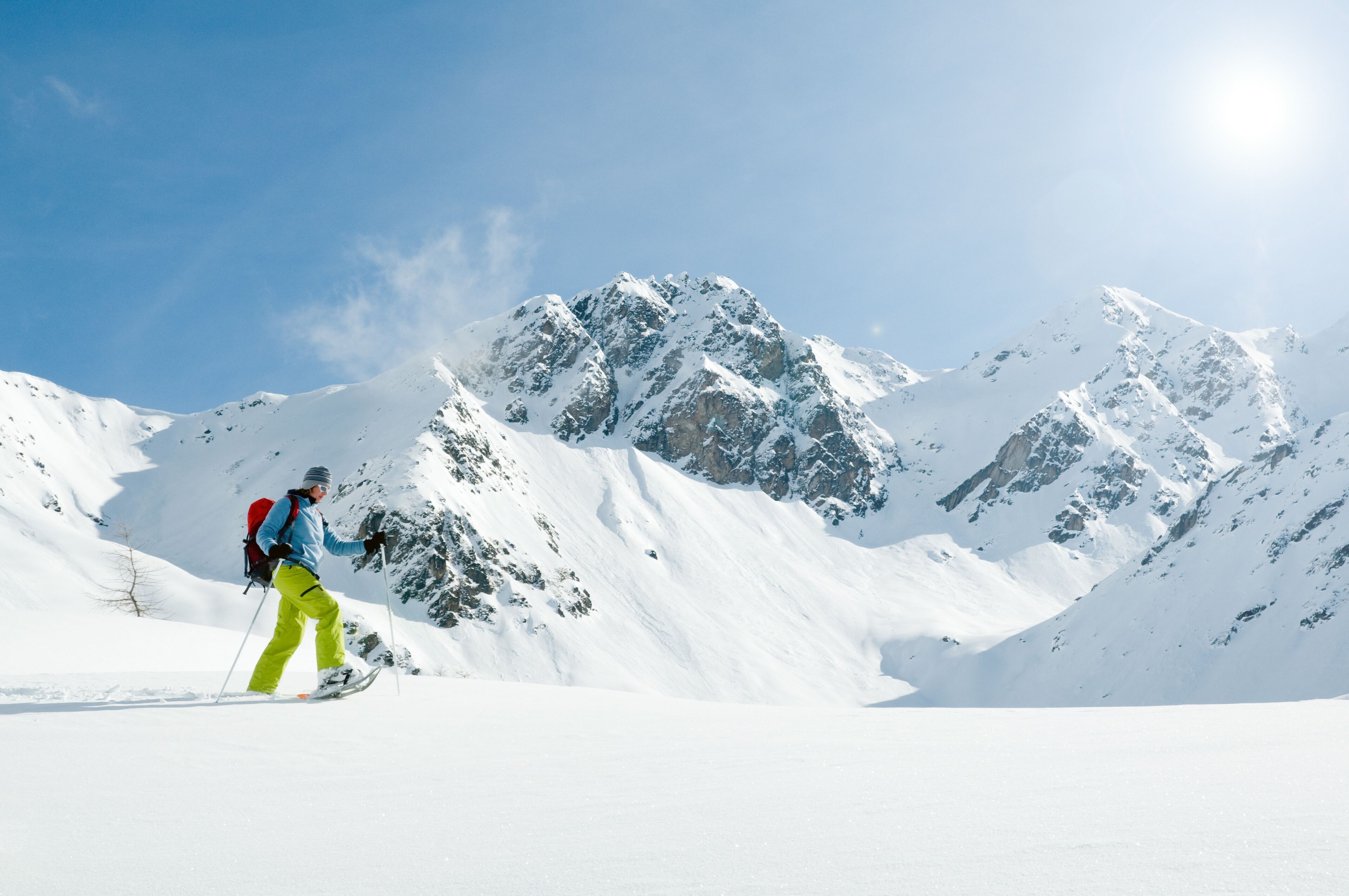 Une personne fait du ski sur une montagne enneigée, sous un ciel dégagé.
