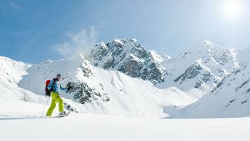 Une personne fait du ski sur une montagne enneigée, sous un ciel dégagé.