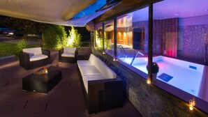 Un área de spa al aire libre con hidromasaje, asientos y una pared de piedra.