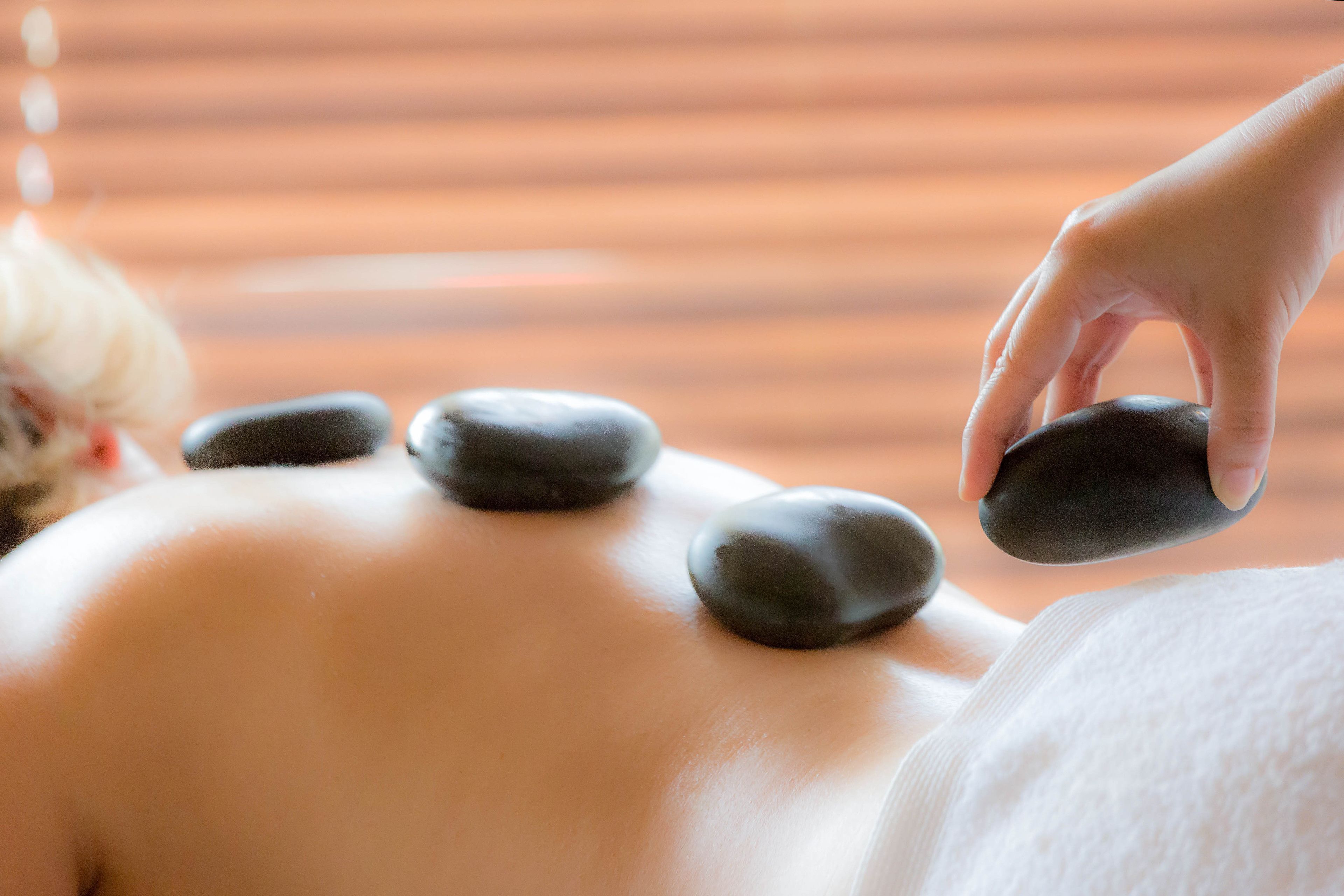 A person receiving a stone massage with four stones placed on their back.