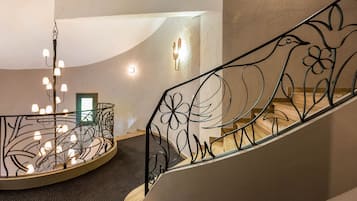 Una escalera curva con barandilla de metal decorativa que presenta motivos florales.