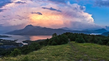 A mountainous landscape with a lake, forested areas, and a clear sky.