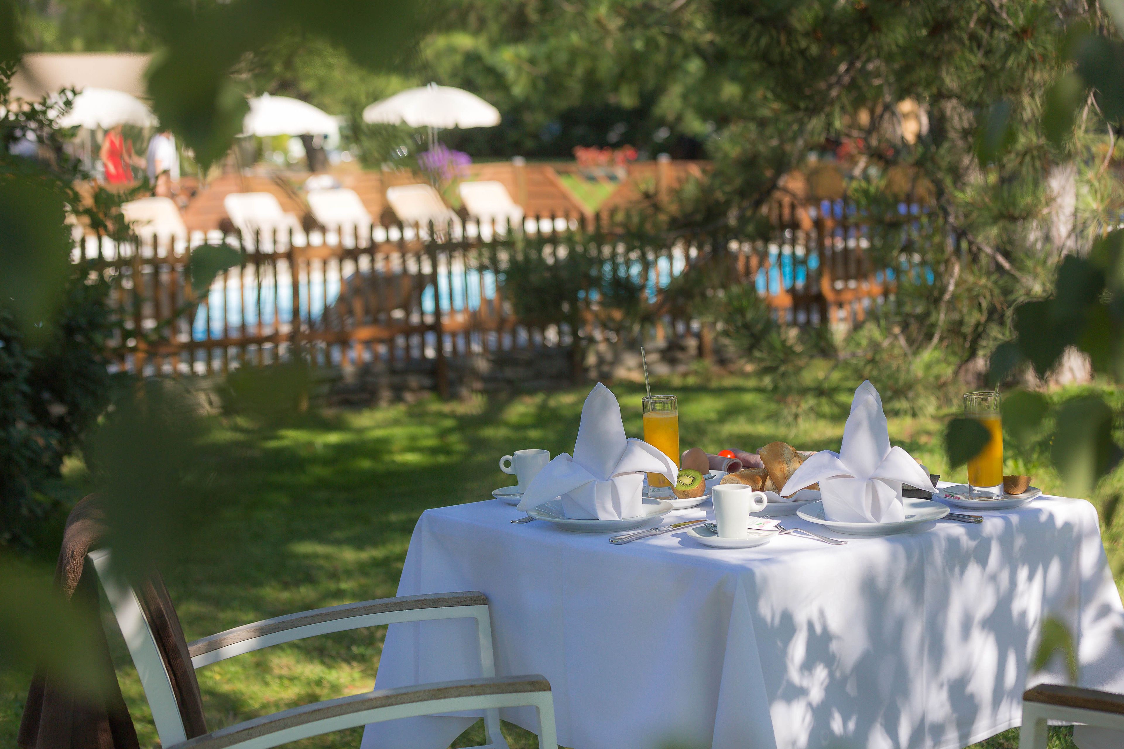 A table set for breakfast with a view of a pool and lounge chairs in the background.