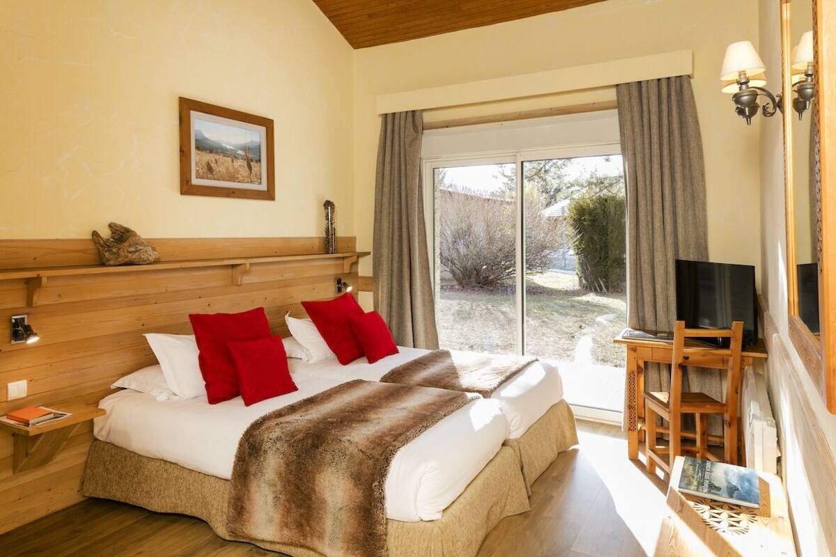 A double bed with red and white pillows, a fur throw, and a wooden headboard.