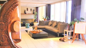 A modern living room with a sectional sofa, a coffee table, and a wooden sculpture. - The Melanesian Port Vila Hotel (Port Vila)