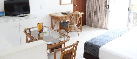A hotel room with a bed, a desk with a chair, a television, and a large mirror.