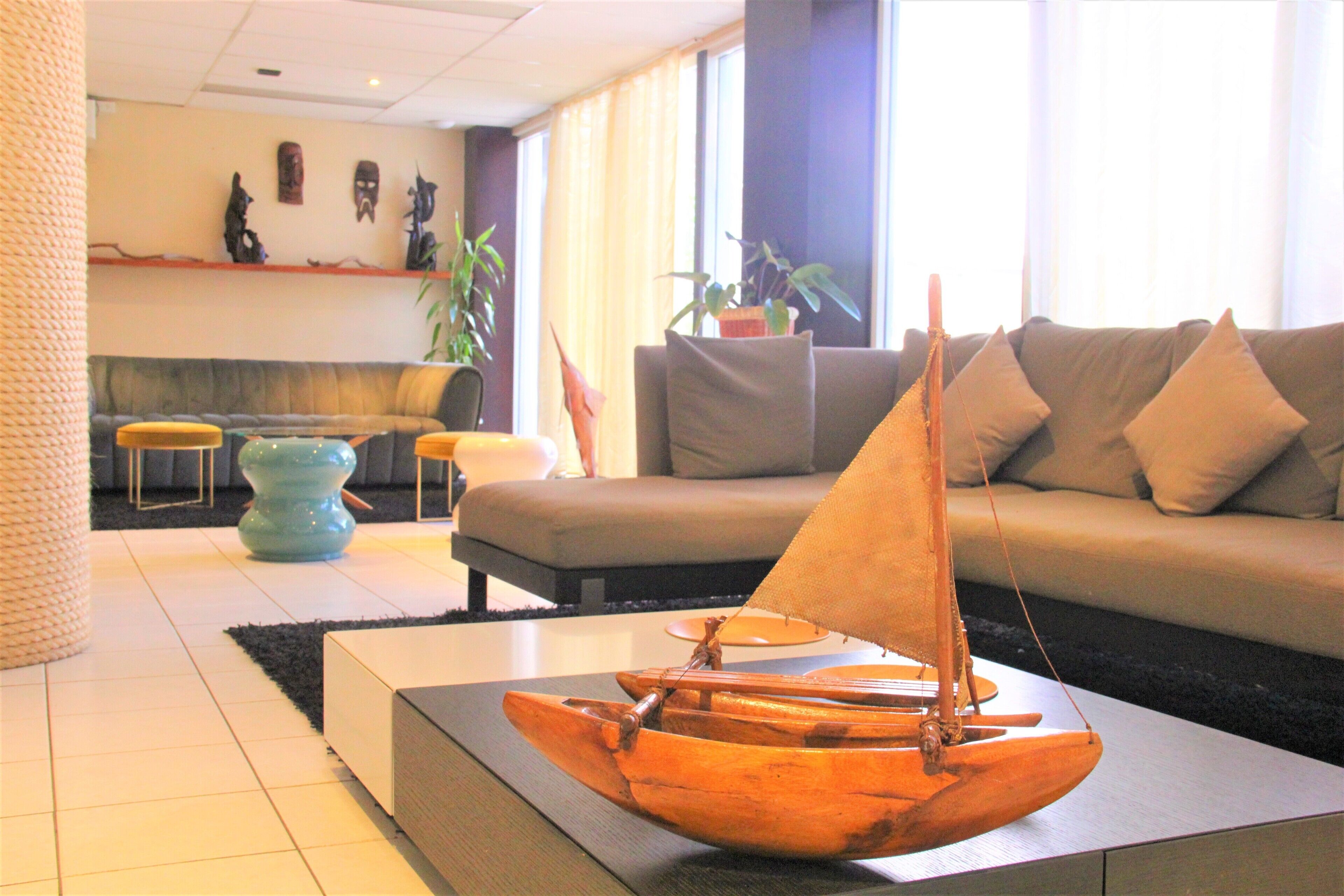 A modern living room with a wooden sailboat model on a table, a sofa, and a coffee table.