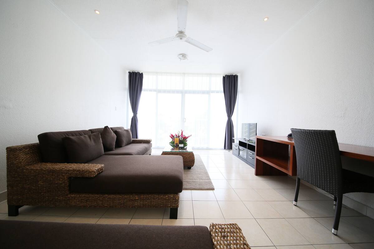 A living room with a sofa, a chair, a TV, and a ceiling fan.