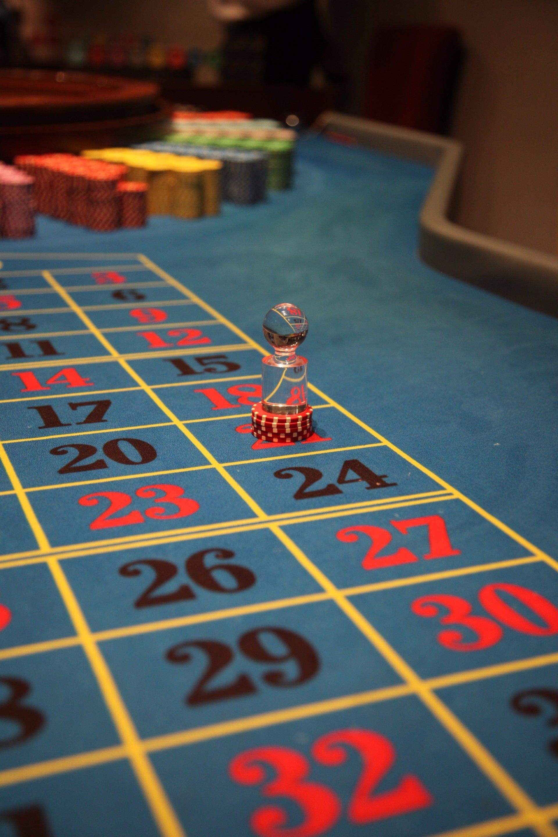 A craps table with a dice tower in the center, numbered betting areas, and stacked chips.