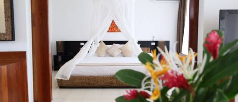 Un dormitorio con una cama bajo un dosel blanco, un televisor y un aire acondicionado instalado en la pared.