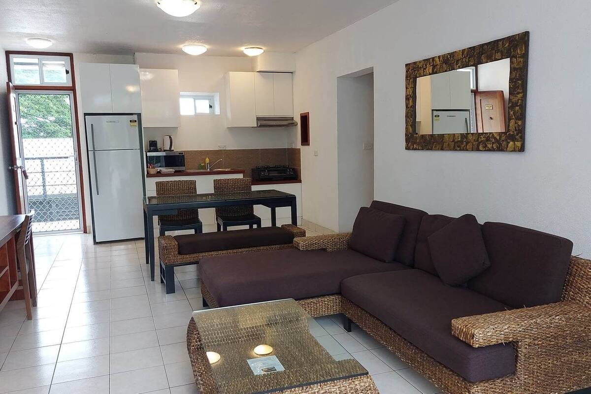 A compact living space with a sofa, coffee table, dining table, and kitchen area.