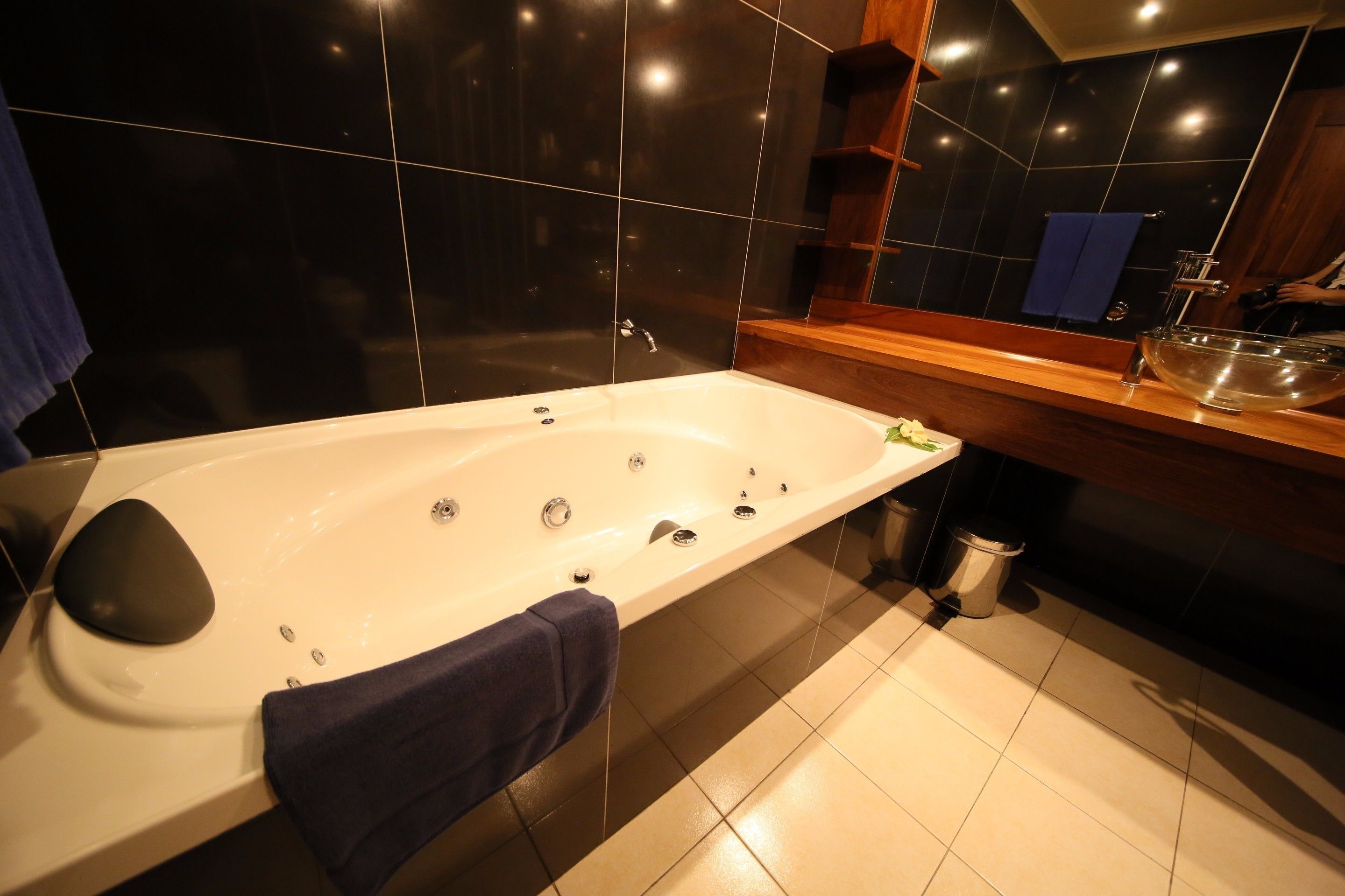 Une salle de bain moderne avec une grande baignoire, un meuble-lavabo en bois et un miroir.