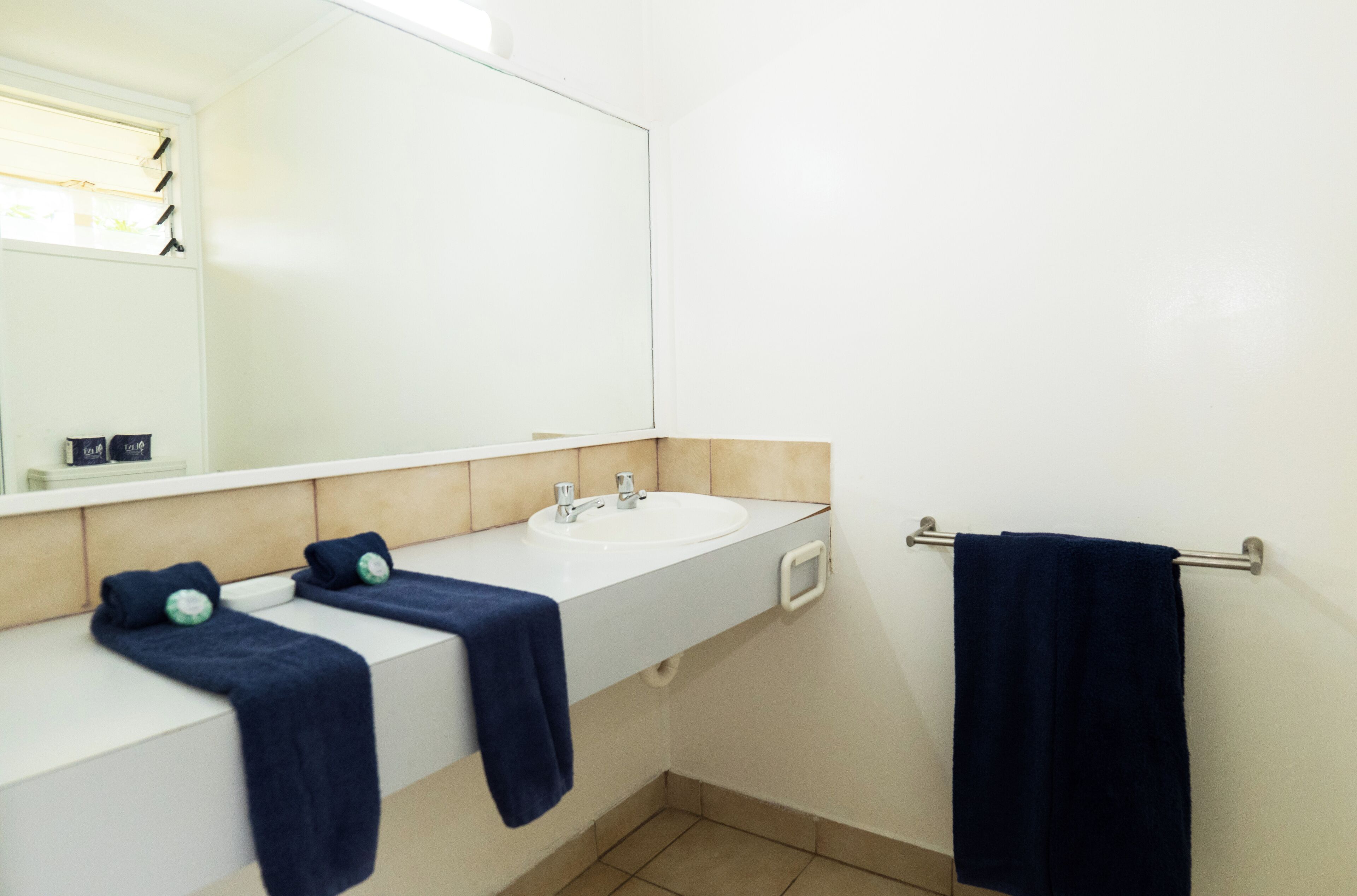 Un baño con dos lavamanos, un espejo y un perchero para toallas.