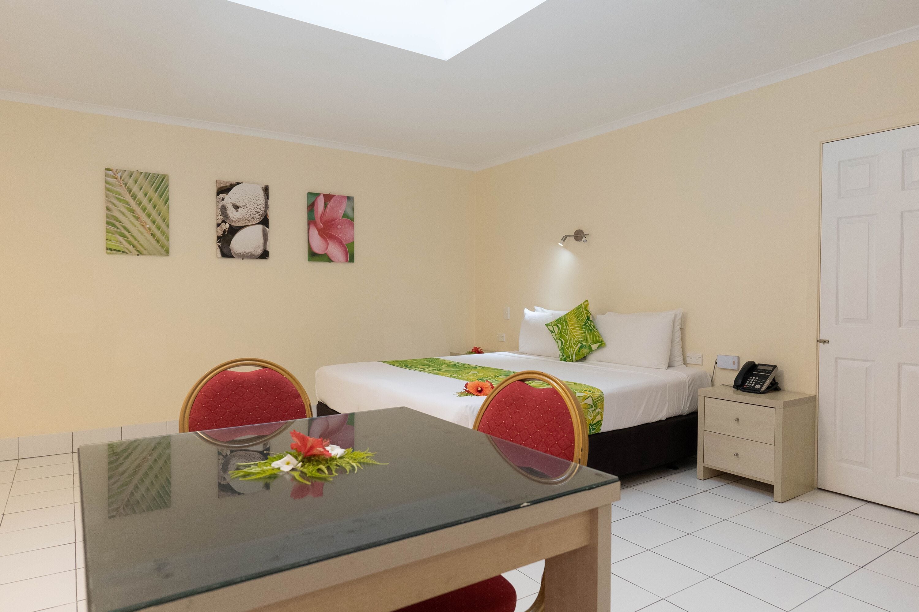 A hotel room with a bed, bedside table, nightstand, and a dining table with chairs.