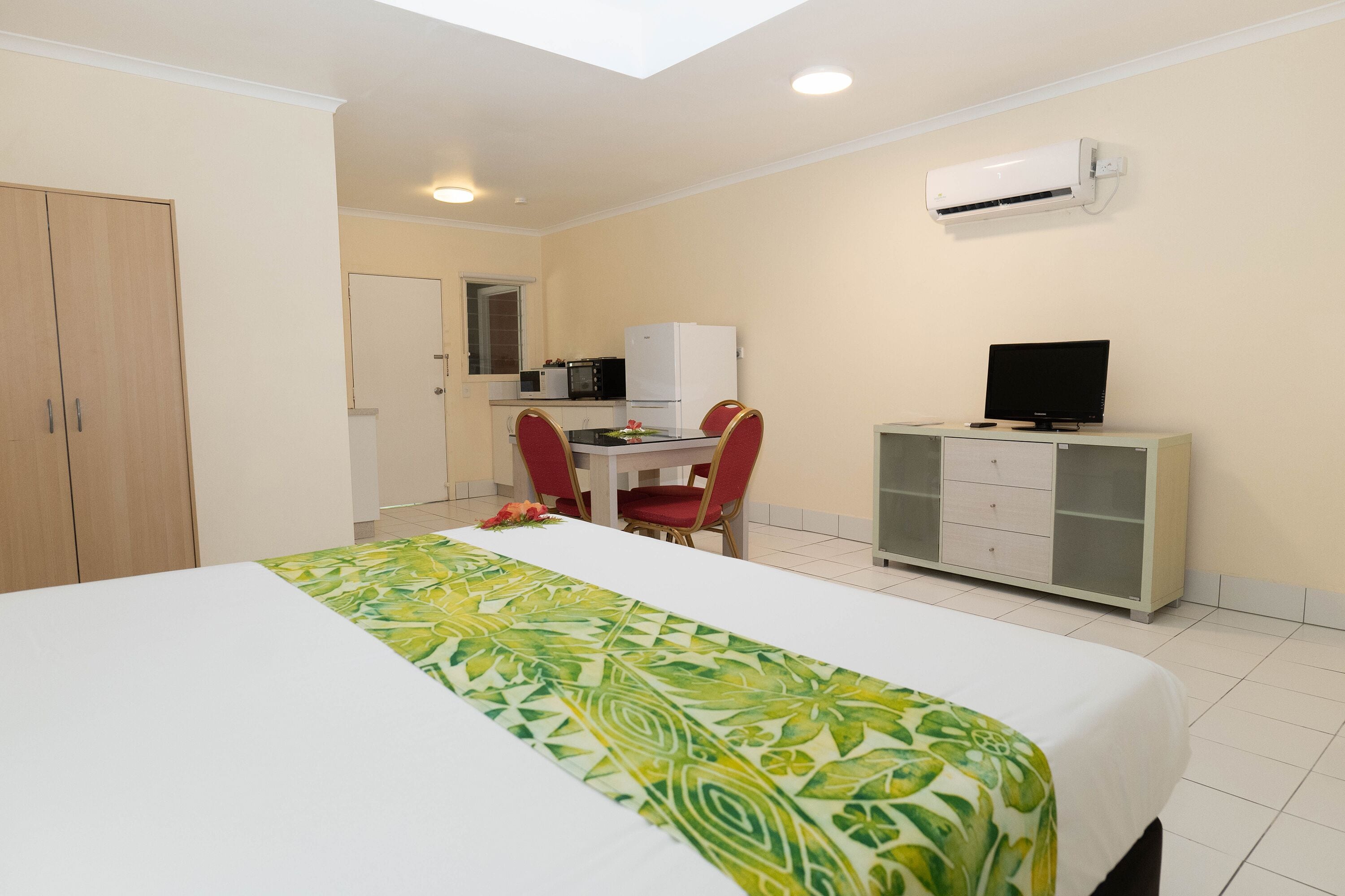 Una habitación de hotel con una cama, un escritorio con silla, televisión y armario.