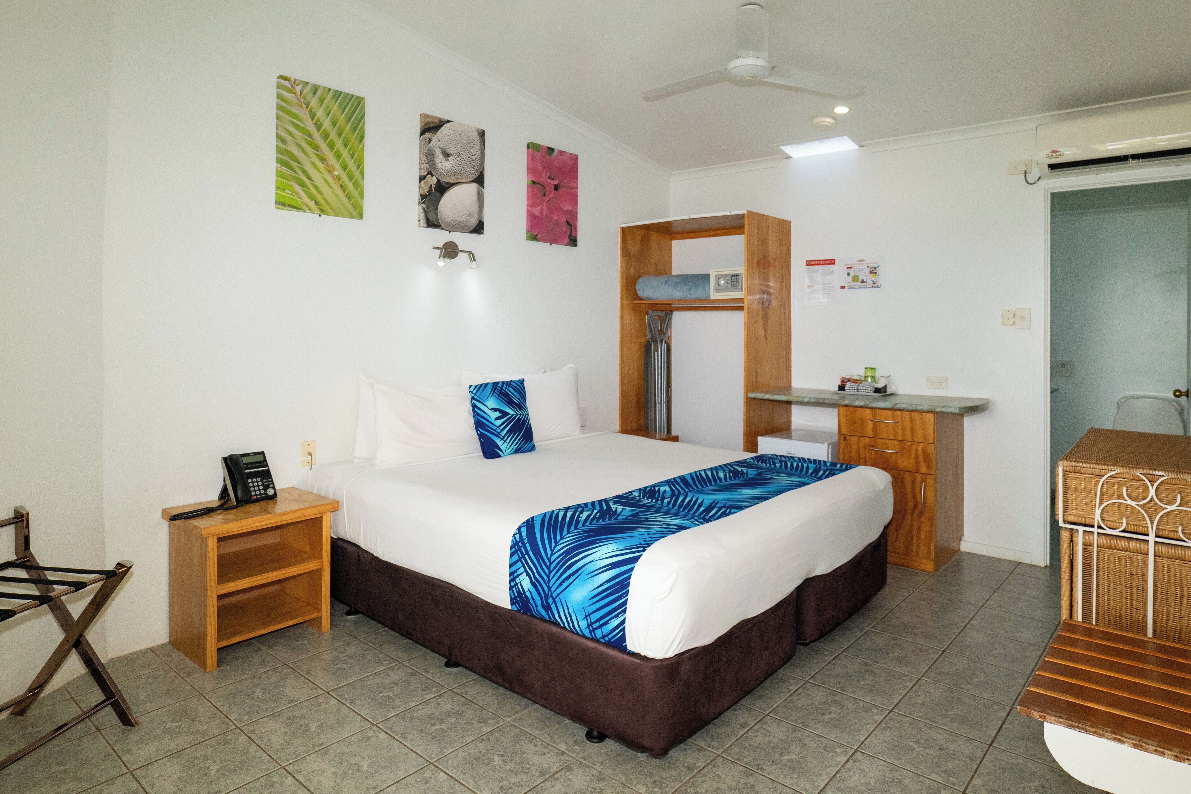 A hotel room with a bed, a wooden nightstand, a desk, and a bathroom.
