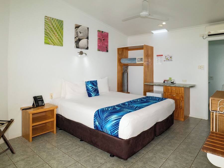 Ein Hotelzimmer mit einem Bett, einem Nachttisch aus Holz, einem Schreibtisch und einem Badezimmer.