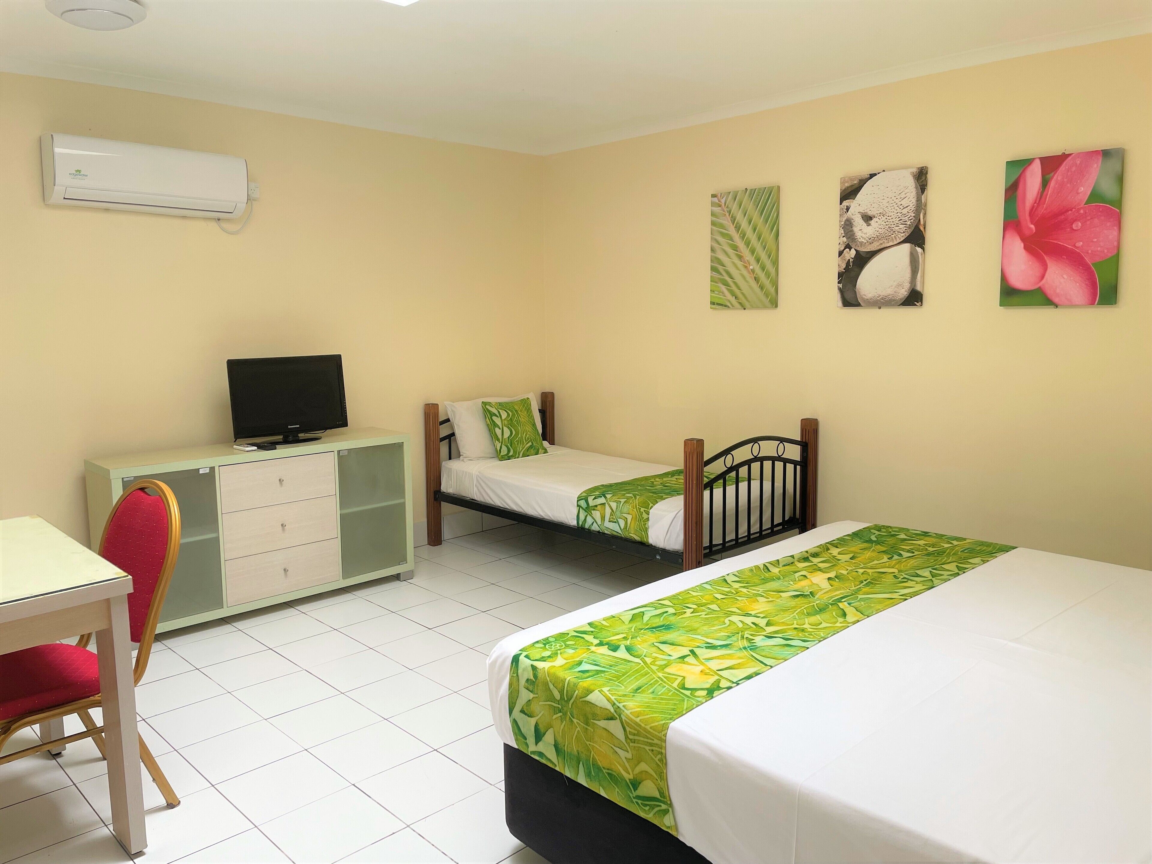 A hotel room with a bed, a desk with a chair, a television, and artwork on the wall.