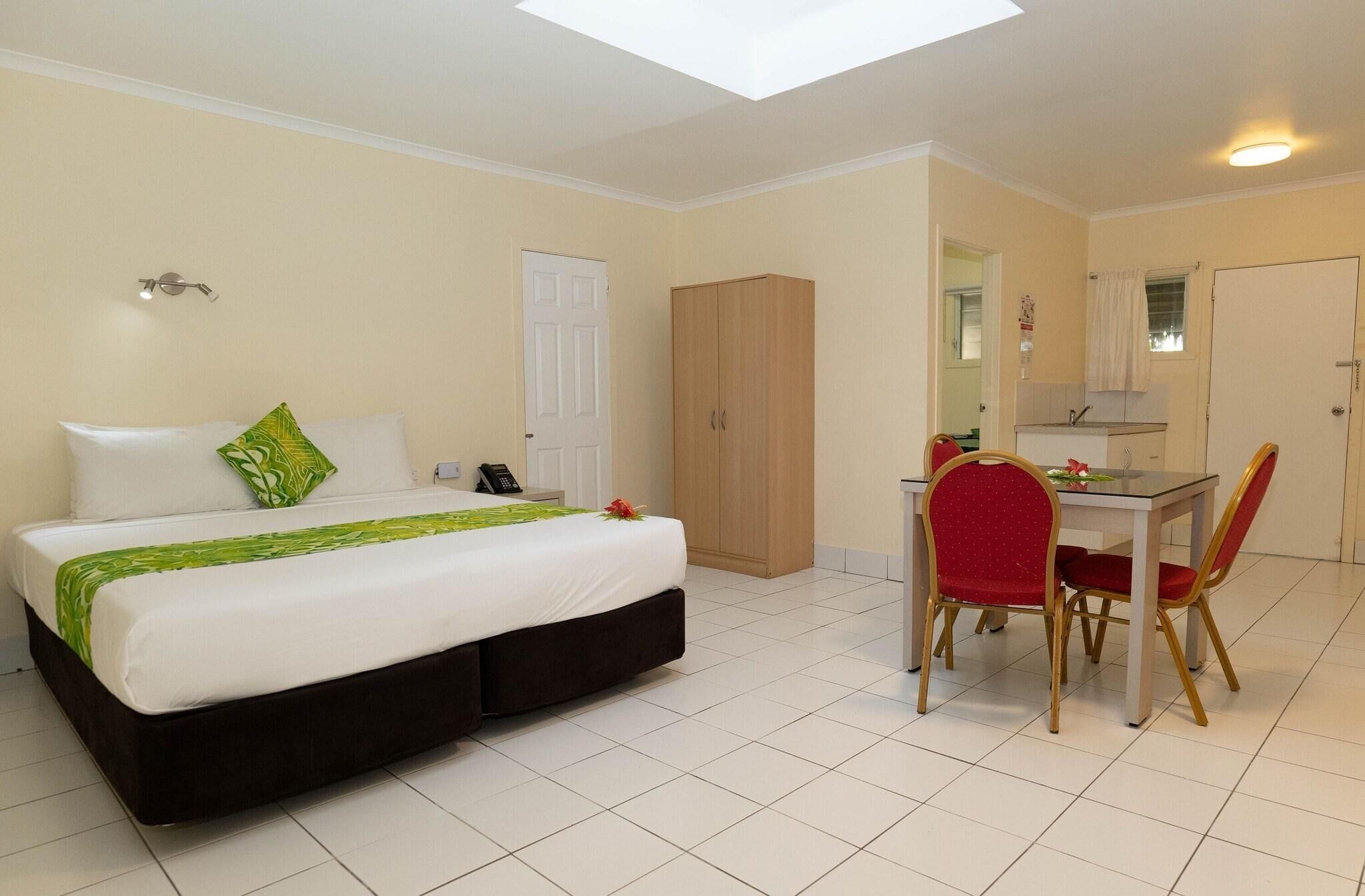 A hotel room with a bed, a desk with a chair, a wardrobe, and a bathroom.