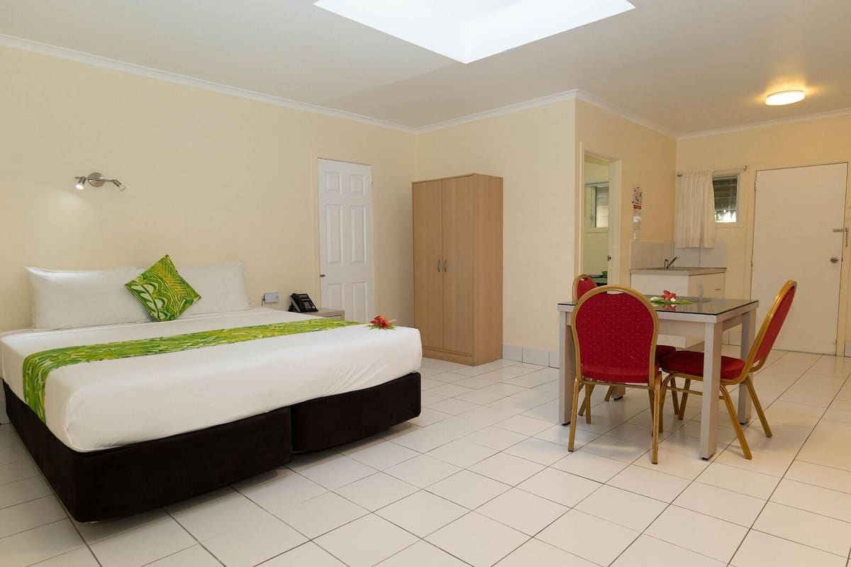 A hotel room with a bed, a desk with a chair, a wardrobe, and a bathroom.