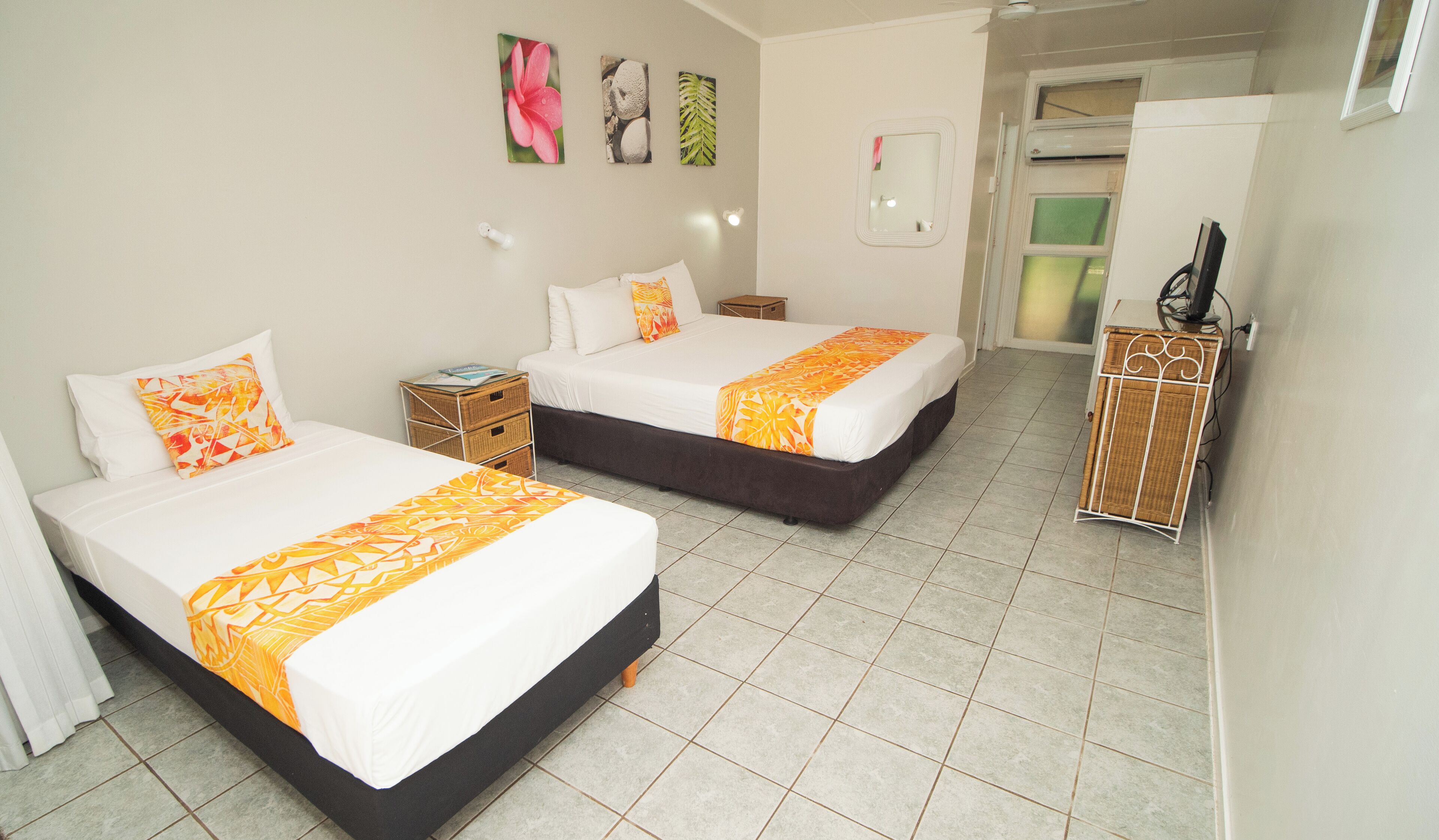 Habitación de hotel con dos camas, una mesita de noche, un armario y un espejo.